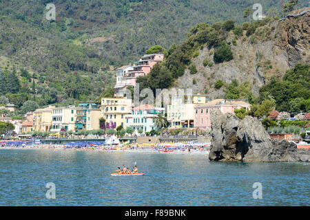 Monterosso, Italien - 7. Juli 2015: Menschen paddeln in einem Kanu, Schwimmen und Sonnenbaden am Strand von Monterosso auf Cinque Terre Stockfoto