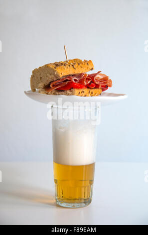 Typische spanische Tapas: iberischer Schinken mit rotem Pfeffer Sandwich auf ein Glas Bier. Stockfoto