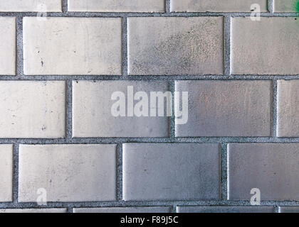 Detail einer Backsteinmauer mit Silberfarbe drauf Stockfoto