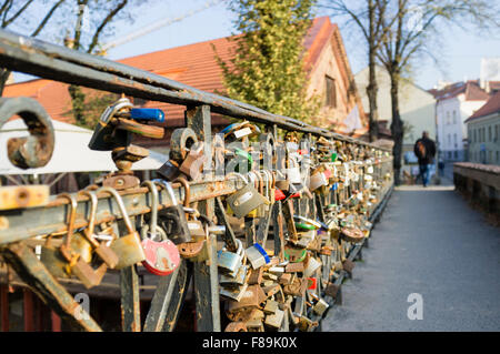 Ein Mann geht vorbei an Liebe Sperren auf Brücke über Fluss Vilnia in Richtung der selbsternannten unabhängigen Republik Uzupis Bezirk in Vil Stockfoto