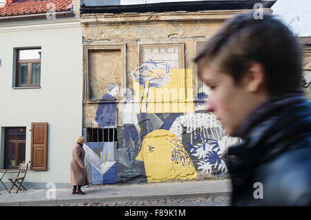 Die Menschen gehen vorbei an Graffitis an der selbsternannten unabhängigen Republik von Uzupis bohemian District. Vilnius, Litauen Stockfoto