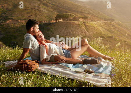 Junges Paar mit Picknick auf einer Wiese an einem sonnigen Tag. Kaukasischen Mann und Frau entspannend bei Picknick an einem Sommertag. Stockfoto