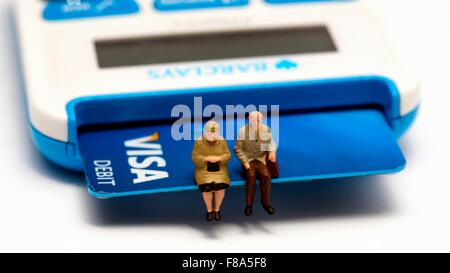 Zwei Miniaturfiguren Rentner sitzen auf einer Visa Debit-Karte Stockfoto