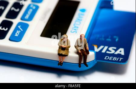 Zwei Miniaturfiguren Rentner sitzen auf einer Pin-Sentry-Maschine mit einer Visa Debitkarte innen Stockfoto