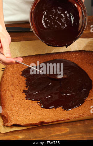 Sahnehäubchen auf Kuchen gießen. Schokoladen-Brownie zu machen. Serie. Stockfoto