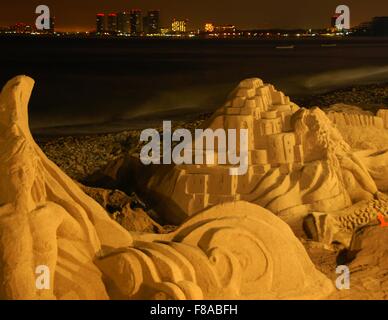 Eine Sandskulptur am Strand in Puerto Vallarta, Mexiko, mit Hotel Lichter im Hintergrund. Stockfoto