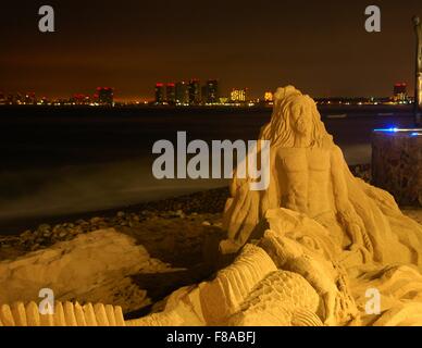 Eine Sandskulptur am Strand in Puerto Vallarta, Mexiko, mit Hotel Lichter im Hintergrund. Stockfoto