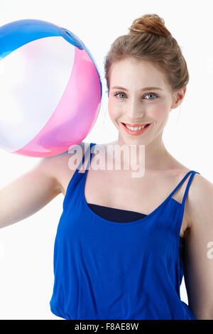 Lächelnde Frau in blauem Hemd mit einem Wasserball auf die Schulter Stockfoto