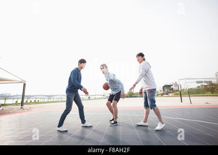 Drei Männer spielen einen Basketball auf dem Basketballplatz Stockfoto