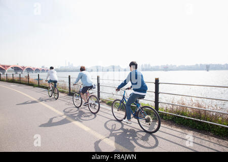 Darstellung von drei jungen Männern, die ihr Fahrrad entlang des Flusses Han River Park zurück Stockfoto