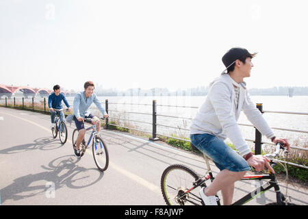 Drei junge Männer ihre Fahrradfahren entlang der Flussufer am Han-Fluss Park lächelnd Stockfoto