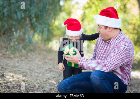 Glücklicher Vater junge Tochter A Weihnachten Geschenk im Freien geben. Stockfoto