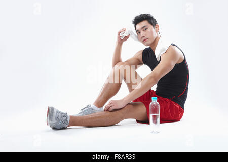 Mann in Sportbekleidung Sitzung wischte sich den Schweiß mit Wasserflasche starrte auf Vorderseite Stockfoto