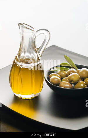 Olivenöl und Oliven auf einer schwarzen Platte. Stockfoto