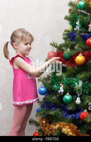 kleines Mädchen schmückt einen Weihnachtsbaum mit Kugeln Stockfoto