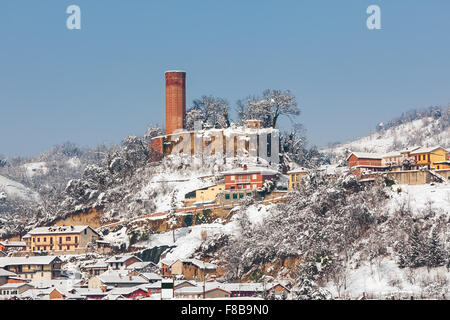 Kleines Dorf und alten mittelalterlicher Turm auf Hintergrund mit bedeckt Schnee im Piemont, Norditalien. Stockfoto