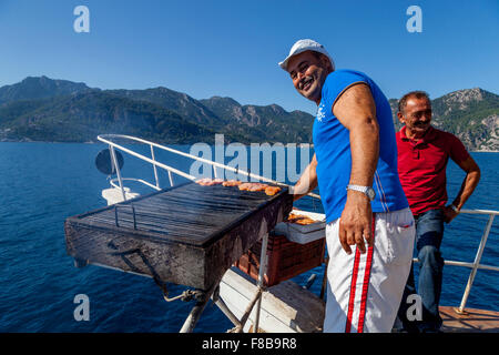 Boot-Mitarbeiter kochen ein Barbeque Mittagessen für Touristen während eine Boot Reise, Marmaris, Provinz Mugla, Türkei Stockfoto