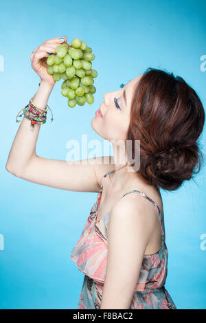 Frau im Sommer tragen essende Trauben mit geschlossenen Augen Stockfoto