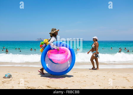 RIO DE JANEIRO, Brasilien - 15. März 2015: Strand Verkäufer verkaufen bunte Strandspielzeug trägt seine Ware Ipanema Strand entlang. Stockfoto