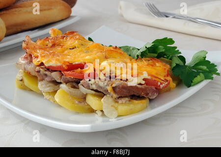 Gebackene Kartoffeln mit Zwiebeln, Fleisch und Tomaten mit Käse Stockfoto