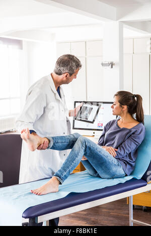 Arzt untersucht die Knöchel einer Patientin. Stockfoto