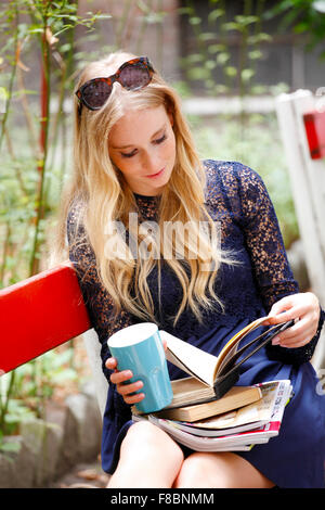 Porträt von attraktiven Studentin Buch zu lesen, beim Sitzen am Campus-Bereich. Studentisches Leben. Stockfoto