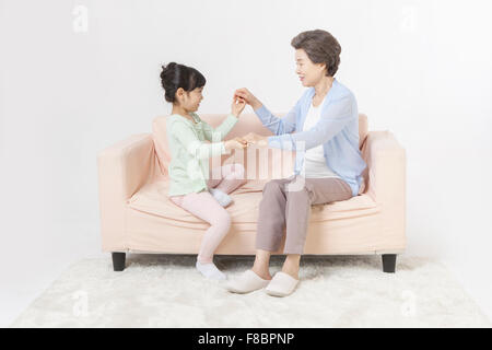 Großmutter und Enkelin Hand in Hand zusammen und Spaß auf einer Couch sitzen und sahen einander Stockfoto