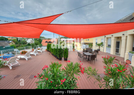 Terrasse im Sommer mit Schatten Segel, Blumen und Liegestühle Stockfoto