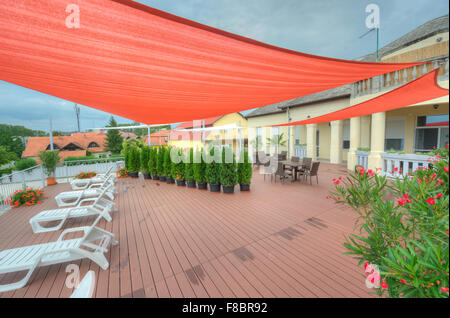 Terrasse im Sommer mit Schatten Segel, Blumen und Liegestühle Stockfoto