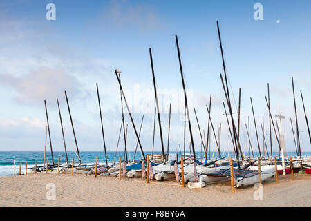 Segelboote liegen in einer Reihe auf den Sandstrand von Calafell, Küste des Mittelmeeres, Spanien Stockfoto