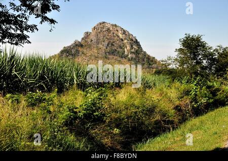 Kanchanaburi, Thailand: Dramatische Karst-Rock-Formation entlang des Kwai Noi Flusses erhebt sich über einem Feld von Zuckerrohr Stockfoto