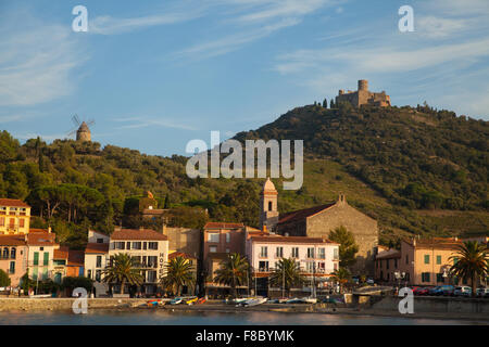 Schönen Abendlicht auf die Stadt Collioure, Südfrankreich, mit der historischen Windmühle & Fort Saint-Elme im Hintergrund. Stockfoto