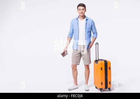 Mann im casual-Outfits stehen mit seiner Hand in der Tasche hält seinen Pass mit einem Flugticket und stand neben seinem Stockfoto