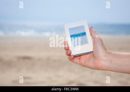 Strand Foto auf einem Smartphone in out-fokussierte Wirkung mit dem Hintergrund des Strandes von einer Hand gehalten Stockfoto