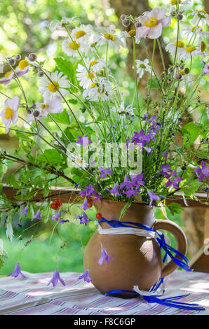 Krug mit einem Bouquet von Sommerblumen auf einem Tisch im Garten Stockfoto