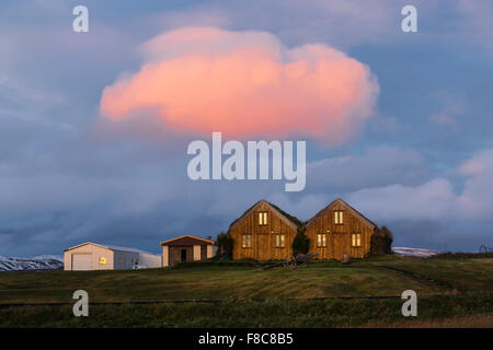 Rasen, die abgedeckten Häusern am Modrudalur. Wunderschöne rote Wolke über Häuser. North Island Stockfoto