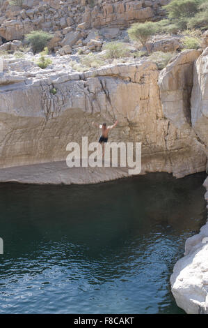 Man springt von einer Klippe im Wadi Bani Khalid, eine natürliche Schlucht-Formation von Felsen und kristallklaren pools Stockfoto