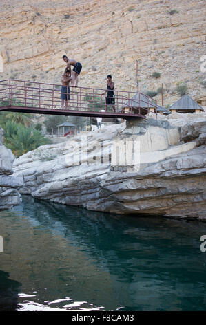 Mann springt von einer Brücke ins Wasser im Wadi Bani Khalid, eine natürliche Schlucht-Formation von Felsen und kristallklaren pools Stockfoto