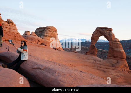 Arches-Nationalpark, Utah, USA. Ein weiblicher Touristen nimmt eine Selfie vor Delicate Arch. Stockfoto