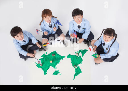 Hohen Winkel von Grundschülern in Schuluniformen sitzen und blickte mit Fahnen in den Händen und eine Welt Stockfoto
