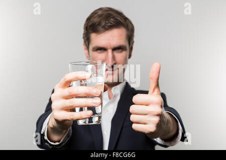 Blonden europäischen Geschäftsmann hält ein Glas Sekt und ein Schläge direkt auf die Kamera vor einem Gradie aufgeben Stockfoto