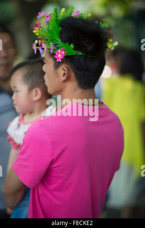 Chinesischer Mann tragen farbige T-shirt mit grünen Blumen um seinen Kopf Stockfoto