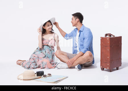 Mann im sitzen auf dem Boden mit einer Frau im Kleid und einen Hut und ihrem Hut berühren beide sahen einander mit casual-outfits Stockfoto