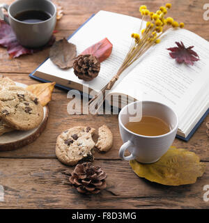 Buchen Sie mit getrockneten Blüten und Laub Dekoration mit einer Tasse Tee und Kekse in Herbststimmung Stockfoto