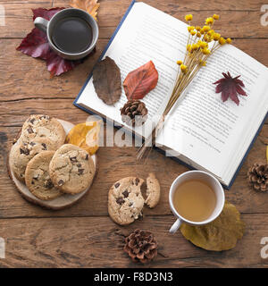 Hohen Winkel eines Buches mit getrockneten Blüten und Laub Dekoration mit Tassen Tee und Kekse in Herbststimmung Stockfoto