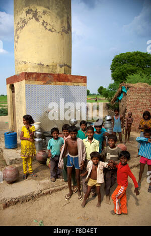 Kinder posieren vor einer Wasserstelle in Indien Stockfoto