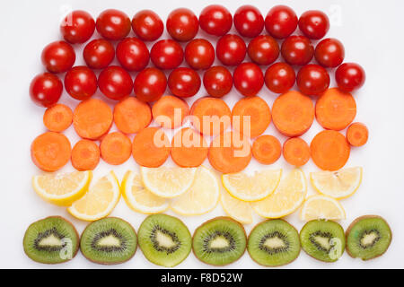 Cherry-Tomaten, Karotten Scheiben, Zitronenscheiben und Kiwi-Scheiben, die in Reihen angeordnet Stockfoto