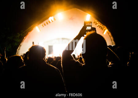 Rückansicht von den Massen von Menschen, die mit ihren Handys, die Band, die Zahlen auf der großen Tribute Music Festival, Aberystwyth, August Bank Holiday Wochenende, Sommer 2015 aufzunehmen Stockfoto