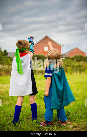 Zwei jungen in hausgemachten Kostümen verkleidet und spielen im Freien, Mini Superhelden an einem Sommerabend, UK Stockfoto