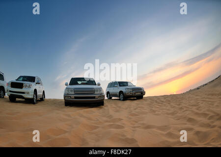 Desert Safari - Jeep Off-Road-Fahrzeuge fahren in der arabischen Wüste bei Sonnenuntergang Stockfoto